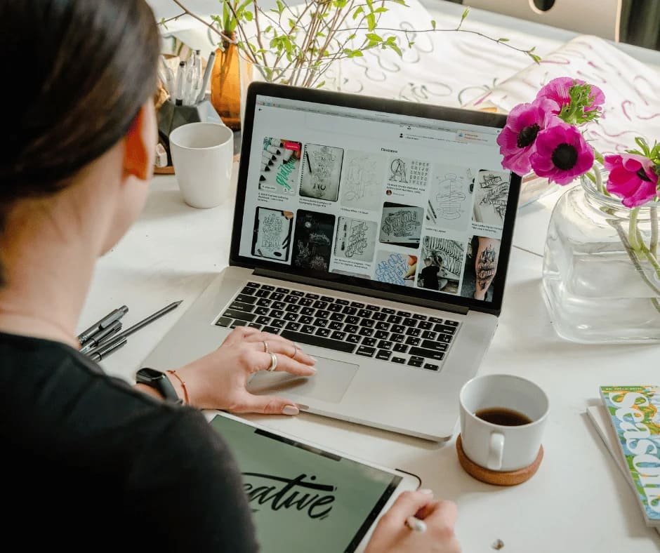 Professional web designer working on website design and creative digital projects on a laptop and tablet.